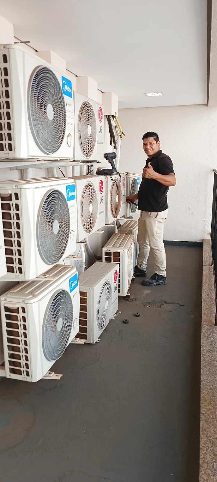 Profissional da Neoclima ao lado de várias unidades condensadoras de ar-condicionado instaladas em sequência.