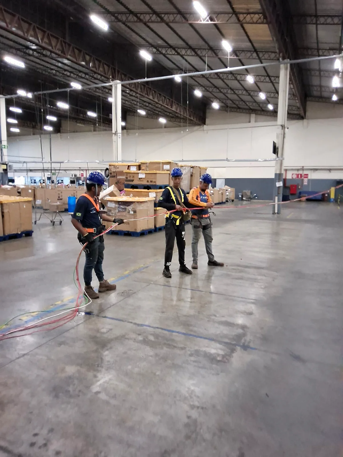 Equipe da GSM mobilizada com capacetes, cintos de segurança e cabos em galpão industrial.